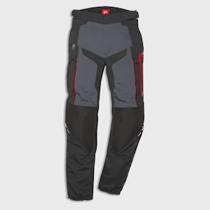 May include: Black and gray motorcycle pants with red accents. The pants feature a reinforced knee area, zippered pockets, and a belt. The design includes a gray panel on the front and red piping along the sides. The pants are designed for motorcycle riding.
