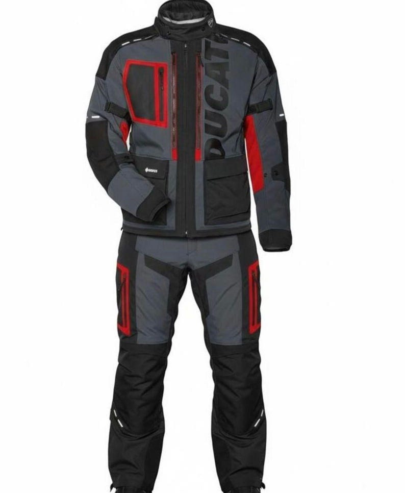 May include: A gray and black motorcycle jacket and pants set with red accents. The jacket features the word "DUCATI" in large gray letters. The set includes multiple pockets and a high collar.