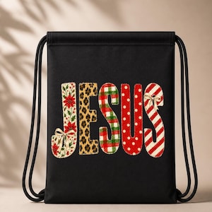 May include: A black drawstring backpack featuring the word JESUS printed in large, decorative letters. Each letter has a unique pattern: poinsettias, leopard print, red and green plaid, red with white polka dots, and red and white candy cane stripes.