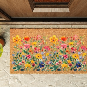 May include: A rectangular doormat with a floral design. The mat features a vibrant array of colorful flowers, including yellow, red, pink, and blue blooms, set against a natural brown background. The flowers are arranged in a dense, watercolor-style pattern.