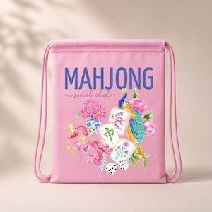 May include: A pink drawstring backpack featuring the blue text MAHJONG social club. The design includes a colourful peacock, pink flowers, a blue and white vase, a pink dragon, three mahjong tiles, and two white dice with black dots.
