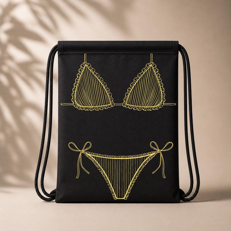 May include: Black drawstring backpack featuring a yellow line drawing of a bikini. The bikini top and bottom are outlined with a scalloped edge and vertical lines. The drawstring is black.