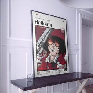 May include: A framed poster for the anime series "Hellsing." The image shows a character with sunglasses and a gun, set against a red and white backdrop. The poster includes the series title and the year 1997.