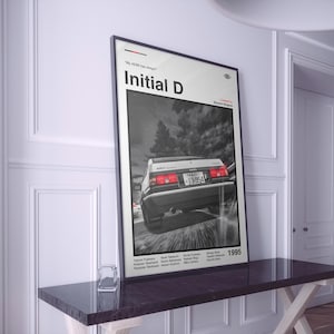 Puede incluir: Póster en blanco y negro de Initial D con un coche en movimiento. El póster muestra el texto "Initial D" y el año "1995". La matrícula del coche dice "13-954".