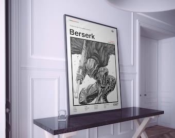 May include: A framed black and white print of the manga series Berserk, depicting a detailed illustration of a knight with a large sword. The print includes the title "Berserk" and the year "1997". The print is displayed on a dark brown table.