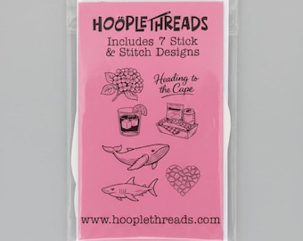 May include: A pink rectangular package labeled HOÖPLETHREADS Includes 7 Stick & Stitch Designs. The front features black line art illustrations of a hydrangea, a drink, a picnic basket, a whale, a shark, a heart, and the text Heading to the Cape.