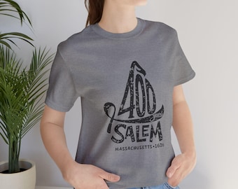May include: A heather grey short-sleeve t-shirt featuring a black distressed graphic design. The print displays the text 400 years, SALEM, and MASSACHUSETTS 1626 in a stylized font. The shirt has a crew neckline and a standard fit.