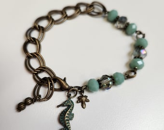 Handmade brass and aqua / blue-green and iridescent glass beads with seahorse and leaf charm