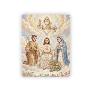 Op de afbeelding: Een rechthoekige legpuzzel met een religieuze illustratie van Jezus, Maria en Jozef te midden van wolken. Een kleine groene draak zit aan de voeten van Jezus, die een hart op zijn borst heeft. De tekst JESUS + MARY + JOSEPH staat onderaan.