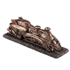 Puede incluir: Una figura decorativa de tren con acabado en bronce metálico y detalles en tono cobre. La locomotora presenta intrincados adornos, tuberías expuestas y pequeños detalles circulares rojos, montada sobre una base negra texturizada.