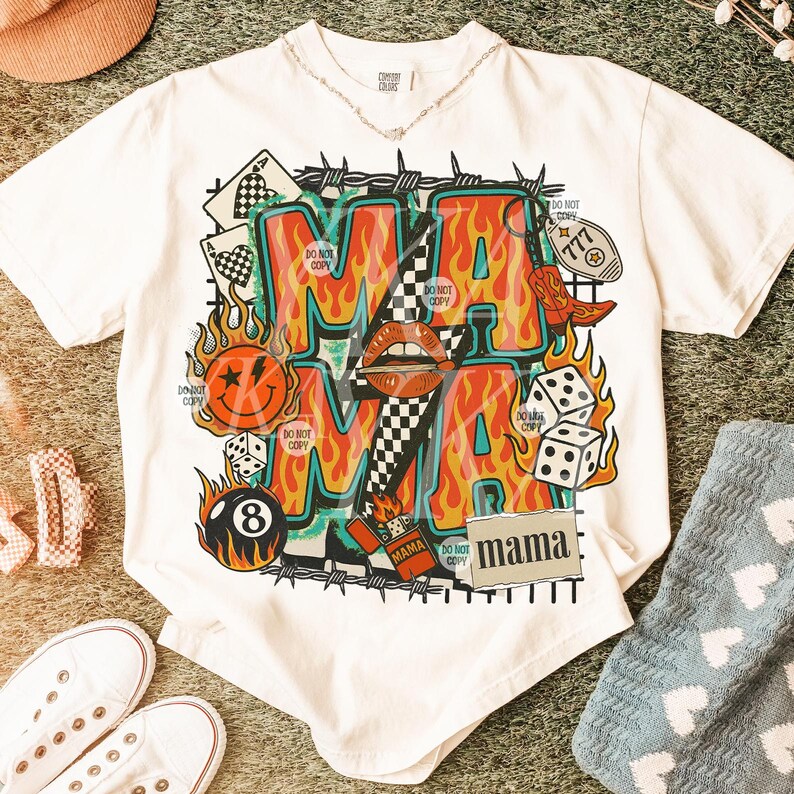 Puede incluir: Camiseta blanca con un dise&ntilde;o gr&aacute;fico audaz. El dise&ntilde;o presenta la palabra "MAMA" en llamas naranjas, rodeada de dados, una carita sonriente y una bota de vaquero. La camiseta tambi&eacute;n tiene el texto "DO NOT COPY".