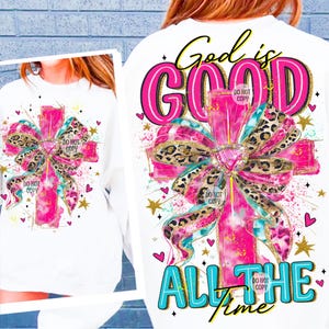Könnte beinhalten: Weißes Sweatshirt mit einem großen rosa Kreuzdesign. Das Kreuz hat eine Schleife mit Leopardenmuster, türkisfarbene Akzente und den Text "God is GOOD ALL THE time". Das Design enthält Herzen und Sterne.