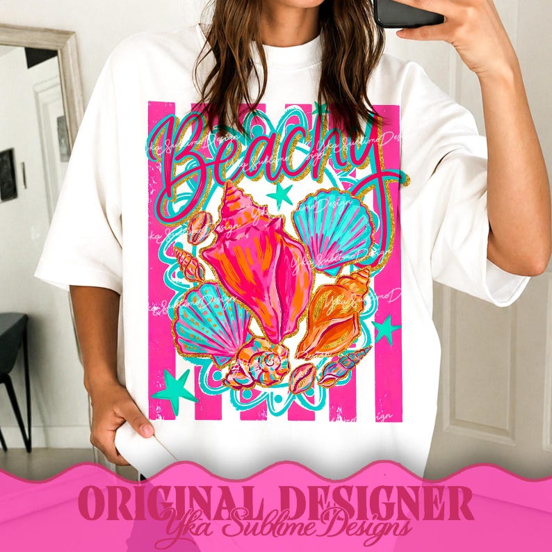 Op de afbeelding: Wit T-shirt met een levendig "Beachy" ontwerp. Het ontwerp bevat kleurrijke schelpen in roze, oranje en turquoise, tegen een roze en wit gestreepte achtergrond. Het shirt heeft ook turquoise sterren en decoratieve elementen.