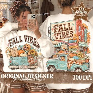 May include: A white long-sleeve sweatshirt featuring a graphic print of a teal vintage pickup truck loaded with pumpkins, sunflowers, and a golden retriever. The text reads Fall Vibes, Good Things Grow Here, Support Local Farmers, and Autumn.