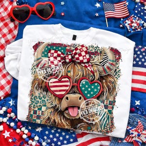Puede incluir: Camiseta blanca de manga larga con un gr&aacute;fico de vaca de las Tierras Altas que lleva gafas de sol en forma de coraz&oacute;n con detalles en rojo y azul. La vaca tiene un lazo a cuadros rojo y blanco. La camiseta tiene el texto "YKA DESIGNS".