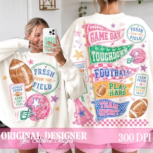 以下が含まれることがあります： 「Fresh From The Field」、「Game Day」、「Touchdown」、「Football」、「Play Hard」、「Team Spirit」という文字と、フットボール、ヘルメット、ペナントのカラフルなグラフィックプリントが施された、白い長袖のスウェットシャツ。