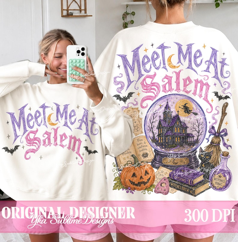 May include: A white long-sleeve sweatshirt featuring a graphic print with the text Meet Me At Salem in purple and pink. The design includes a crystal ball with a house, a flying witch, a jack-o'-lantern, a black cat, a broom, and books.