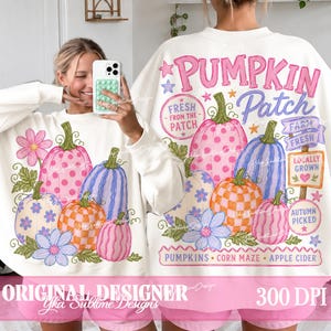 May include: A white long-sleeve sweatshirt featuring a colorful graphic print of pumpkins with polka dot, checkered, and striped patterns, flowers, and text including PUMPKIN PATCH, FRESH FROM THE PATCH, FARM FRESH, LOCALLY GROWN, and AUTUMN PICKED.