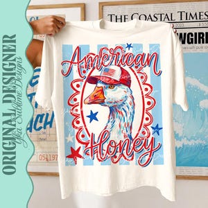 May include: White t-shirt featuring a patriotic design with a goose wearing a hat with an American flag. The words "American Honey" are written in red and blue script, surrounded by stars and stripes.
