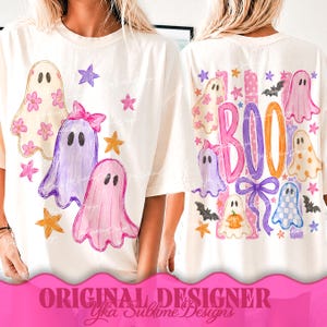 May include: An off-white t-shirt featuring a graphic print of multiple ghosts in various colors and patterns, including floral, solid, and checkered designs, accented with stars, a bow, and the word BOO in large, colorful, hand-drawn style lettering.