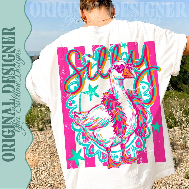 K&ouml;nnte beinhalten: Wei&szlig;es T-Shirt mit einer farbenfrohen Grafik einer Gans mit herzf&ouml;rmiger Sonnenbrille und einer Federboa. Das Wort "Silly" steht in einer verspielten Schriftart &uuml;ber der Gans, mit rosa und t&uuml;rkisfarbenen Akzenten. Das Shirt hat vertikale rosa Streifen.