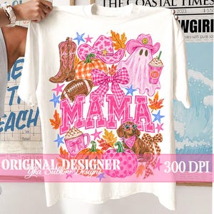 May include: A white t-shirt featuring a colorful graphic print with the word MAMA in large pink letters. The design includes a pink cowboy boot, a pink cow-print cowboy hat, a ghost, a football, pumpkins, a dachshund, and pink bows.