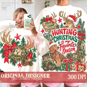 May include: A white long-sleeve sweatshirt featuring a festive graphic print with a deer wearing a Santa hat, a dog in camouflage gear, a rifle, pine trees, red stars, and the text Hunting Christmas is my Favorite Season and Deer Camp Christmas.