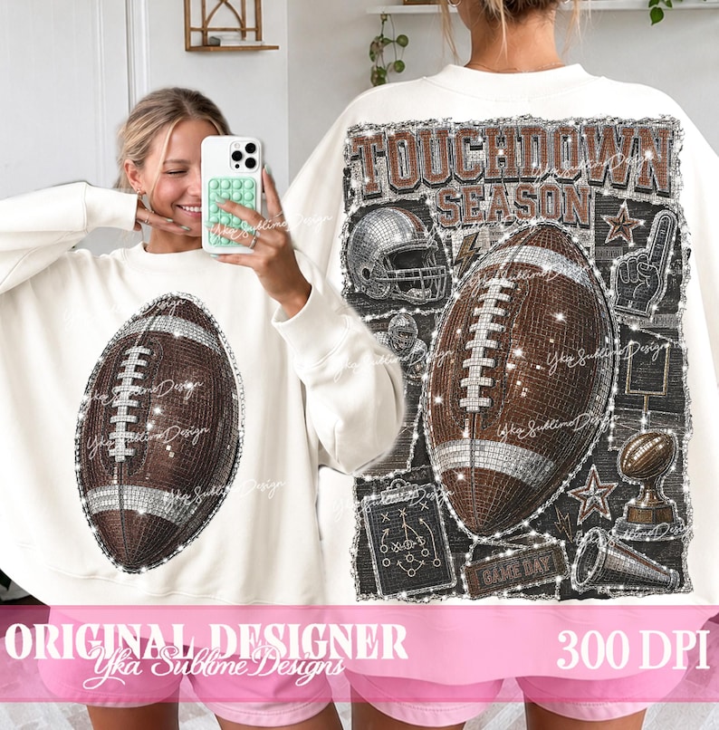May include: A white long-sleeve sweatshirt featuring a brown football graphic on the front. The back displays a large graphic with the text TOUCHDOWN SEASON, a football, a helmet, a foam finger, a trophy, and a play diagram in a glittery style.