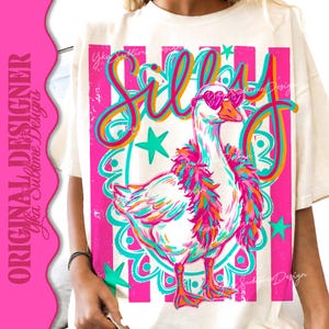 K&ouml;nnte beinhalten: Cremefarbenes T-Shirt mit einer skurrilen Gans, die eine herzf&ouml;rmige Sonnenbrille und eine bunte Boa tr&auml;gt. Das Wort "Silly" ist in einer verspielten Schriftart geschrieben. Das Design umfasst rosa Streifen und t&uuml;rkisfarbene Sterne.