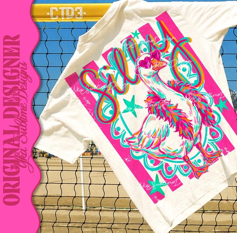 K&ouml;nnte beinhalten: Wei&szlig;es T-Shirt mit einem farbenfrohen Aufdruck einer Gans mit herzf&ouml;rmiger Sonnenbrille und Federboa. Das Wort "Silly" ist in einer verspielten Schriftart geschrieben, mit rosa und t&uuml;rkisfarbenen Akzenten. Das Shirt hat einen rosa-wei&szlig; gestreiften Hintergrund.