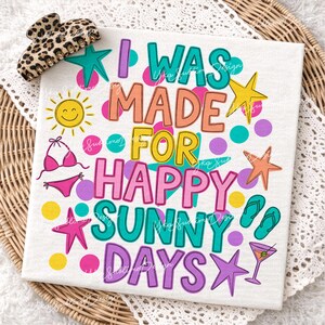 May include: A white t-shirt with the text "I WAS MADE FOR HAPPY SUNNY DAYS" in colorful bubble letters. The design includes a smiling sun, bikini, starfish, flip-flops, and a cocktail. A leopard print hair clip is in the upper left corner.