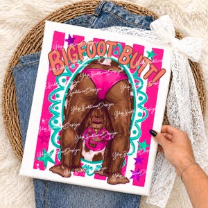 May include: A canvas print featuring a cartoon illustration of Bigfoot's backside in pink underwear. The words "BIGFOOT BUTT!" are in orange and pink. The background has pink and white stripes with teal and purple accents.
