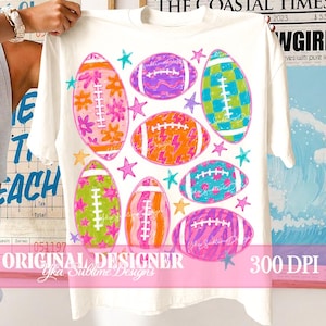 Op de afbeelding: Een wit t-shirt met korte mouwen en een grafische print van zeven American footballs in diverse felle kleuren en patronen, waaronder bloemen, ruiten, bliksemschichten en zebrastrepen, geaccentueerd door kleine kleurrijke sterren.