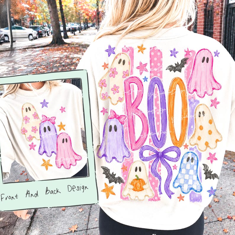 May include: A cream-colored sweatshirt featuring a graphic print of ghosts, stars, bats, and a pumpkin. The design includes the word BOO in large, colorful letters, a purple bow, and pink stripes. The print appears on both the front and back of the garment.