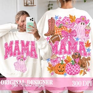 May include: A white long-sleeve sweatshirt featuring a pink graphic print with the text MAMA. The design includes a ghost wearing a cowboy hat, a western boot, a football, a plaid bow, a dachshund, pumpkins, and autumn leaves in pink and orange.