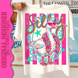 K&ouml;nnte beinhalten: Wei&szlig;es T-Shirt mit einem farbenfrohen Design einer Gans mit herzf&ouml;rmiger Sonnenbrille und Federboa. Das Wort "Silly" steht in verspielten Buchstaben &uuml;ber der Gans. Das Design verwendet Pink, T&uuml;rkis, Orange und Gelb.
