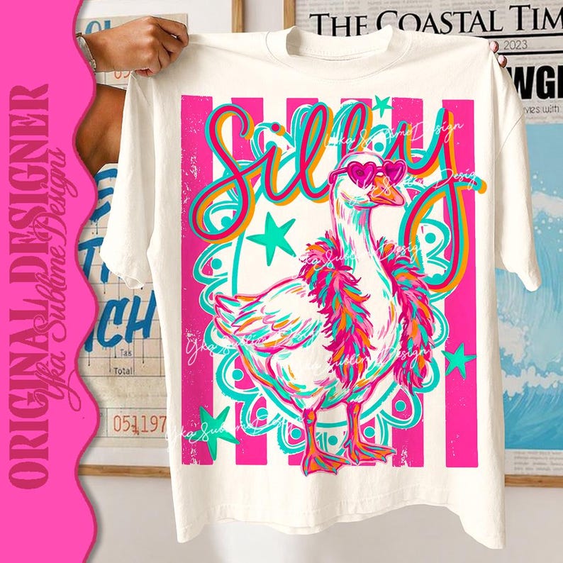 K&ouml;nnte beinhalten: Wei&szlig;es T-Shirt mit einem farbenfrohen Design einer Gans mit herzf&ouml;rmiger Sonnenbrille und Federboa. Das Wort "Silly" steht in verspielten Buchstaben &uuml;ber der Gans. Das Design verwendet Pink, T&uuml;rkis, Orange und Gelb.