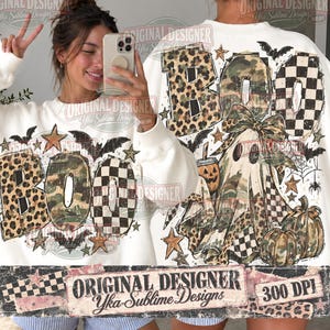 May include: A white sweatshirt featuring a large graphic print of the word BOO in leopard, camouflage, and checkered patterns. The design includes a ghost, pumpkins, bats, stars, and a spider web. The text Original Designer Yka Sublime Designs 300 DPI is visible.