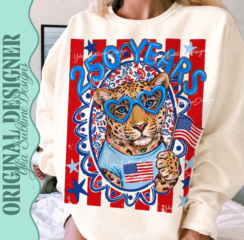 Op de afbeelding: Cr&egrave;mekleurige sweatshirt met een luipaard met hartvormige blauwe bril en een Amerikaanse vlag. Het ontwerp bevat de tekst "250 YEARS" in blauw, tegen een rood, wit en blauwe patriottische achtergrond.