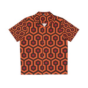 Puede incluir: Camisa de manga corta con botones y estampado geométrico. La camisa presenta un diseño repetitivo de hexágonos marrones y rojo oscuro interconectados sobre un fondo naranja. El cuello es abierto y la camisa tiene un corte relajado.