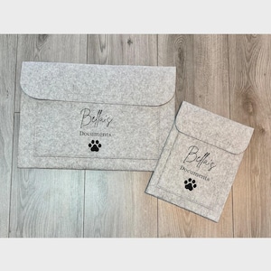 May include: Two grey felt document holders, one large and one small, with a flap closure. Each features the text "Bella's Documents" and a paw print. These holders are designed for document storage.