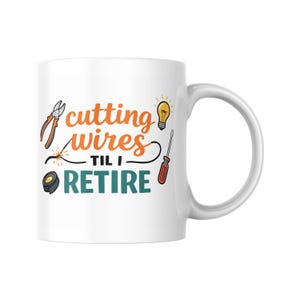 Può includere: Tazza in ceramica bianca con la scritta "cutting wires til I retire" in arancione e verde acqua. La tazza presenta illustrazioni di strumenti come pinze, una lampadina e un cacciavite, suggerendo un tema da elettricista.