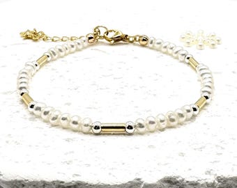 Puede incluir: Una delicada pulsera con pequeñas perlas blancas intercaladas con cuentas de metal dorado y plateado. La pulsera tiene un cierre dorado y una pequeña cadena ajustable. Se ven algunas perlas sueltas.