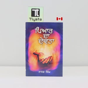 Könnte beinhalten: Ein Buch mit dunkelblauem Einband mit Text in einer Fremdsprache und einer Illustration einer Hand, die eine leuchtende Kugel hält. Das Buch trägt den Titel "Tlysta" und hat eine kanadische Flagge im Hintergrund.