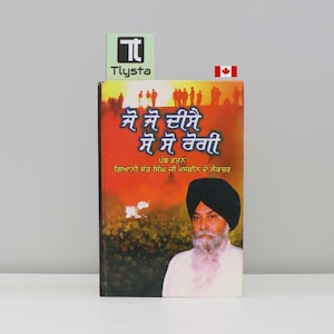 May include: A book with a vibrant cover featuring text in a foreign language, a portrait of a man with a turban and beard, and a group of silhouettes. The book has a green and white logo and a Canadian flag.