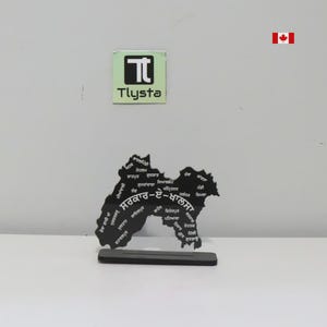 May include: A black wooden map with white text, mounted on a black base. The text includes the words "Tlysta" and "Canada".