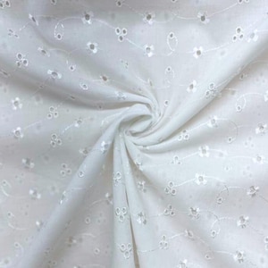 Puede incluir: Tela calada blanca con patrones florales y de puntos bordados. La tela está tejida de forma apretada y tiene una caída suave y fluida. El bordado presenta pequeñas flores y delicadas vides, creando una superficie texturizada.