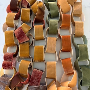 May include: A decorative chain composed of interlocking velvet-textured loops in a variety of autumn-inspired colors including deep red, burnt orange, mustard yellow, golden brown, and olive green, arranged in six vertical columns.