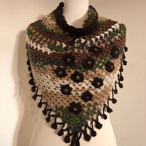 May include: A handmade crochet shawl in shades of brown, green, and cream, decorated with dark brown flower appliqu&eacute;s and beaded centres. The shawl has a triangular shape with a dark brown collar and fringe.