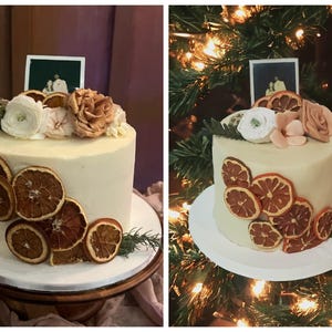 May include: A white wedding cake decorated with dried orange slices, flowers, and a small photo of a couple. The cake is on a wooden cake stand.